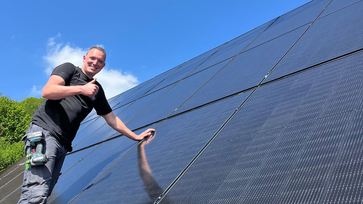 Robin Ehrler neben Photovoltaik-Module in luftiger Höhe